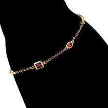 Load image into Gallery viewer, Gold bracelet with red gemstones on a black silhouette of a hand.
